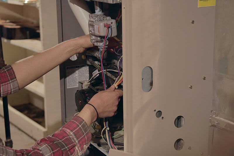 A handyman doing some maintenance on a furnace